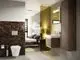 Ideal Standard Badezimmer mit modernem Design, featuring eine braune Wandverkleidung aus Hexagonfliesen, ein WC und ein Waschbecken mit Spiegel an der Wand.